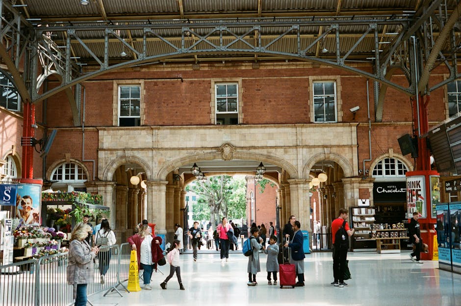 A busy street scene in Westminster, with pedestrians walking along the pavement and crossing the road. The street features historic brick buildings with retail storefronts, one of which displays a sig